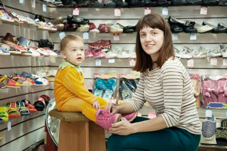 мама примеряет обувь ребенку