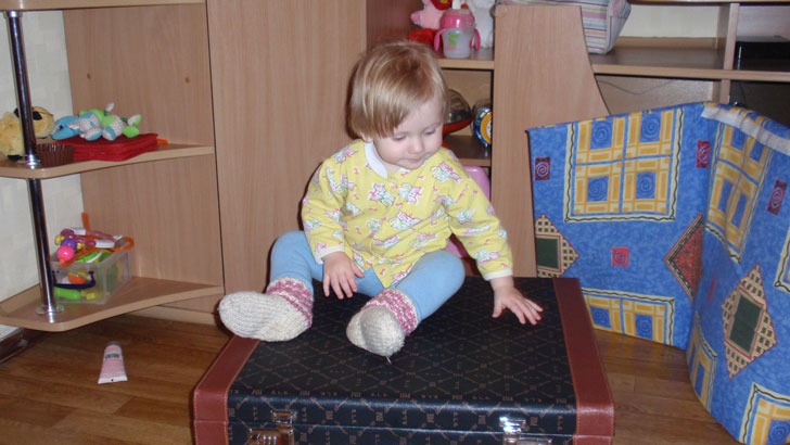 маленький ребенок изучает старый чемодан