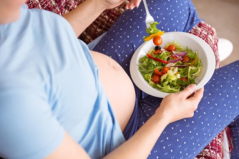 беременная женщина ест овощной салат