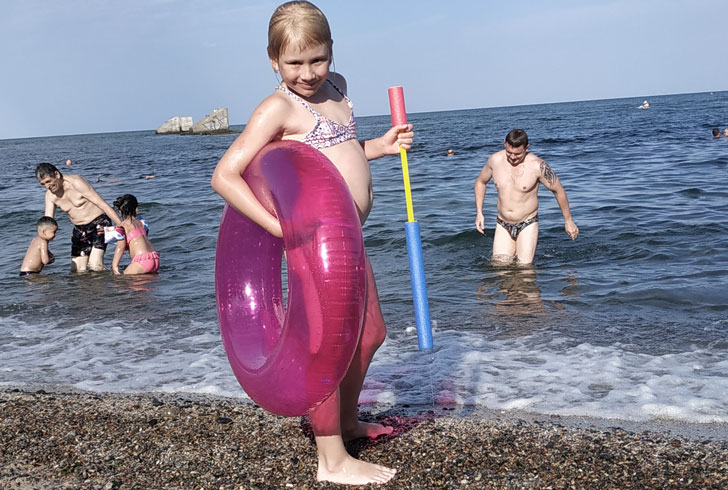 девочка 6 лет с кругом и водным ружьём собирается плавать
