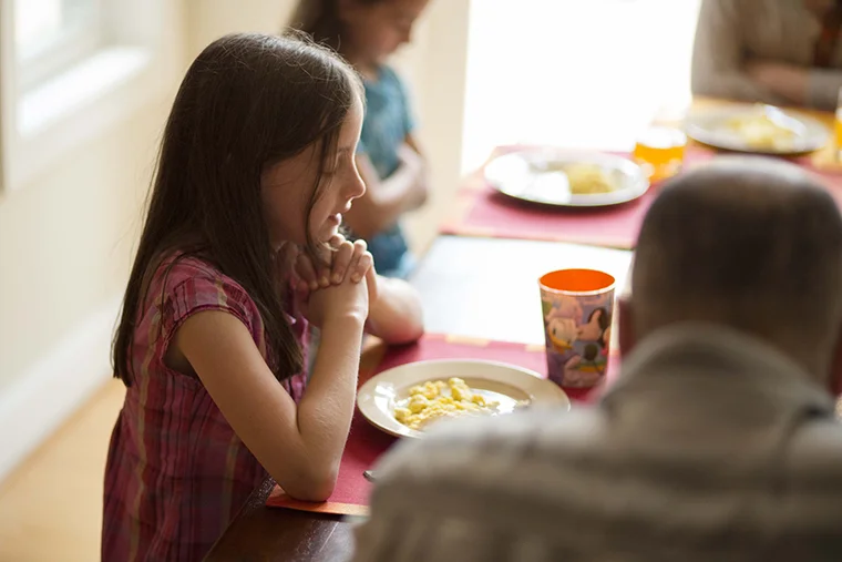 девочка на застольной молитве за обеденным столом