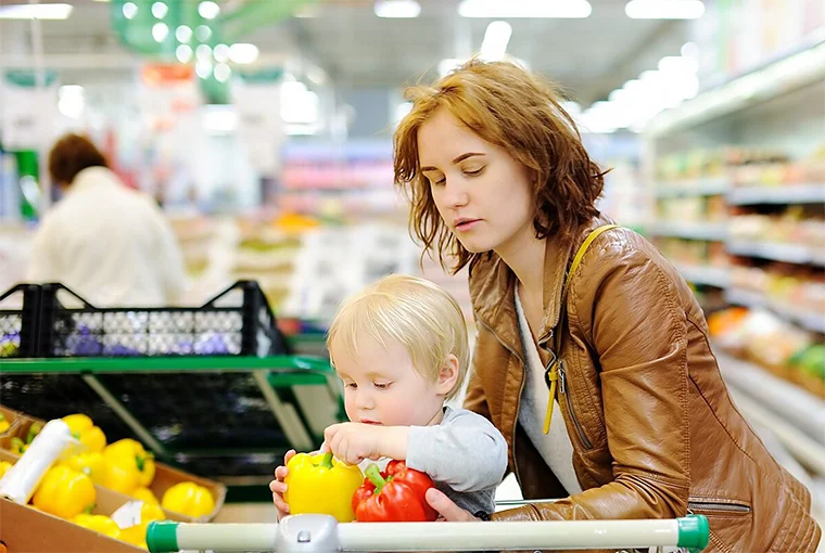 ребенок помогает маме в супермаркете