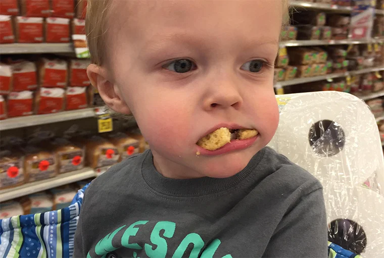 спокойный ребенок ест печенье в магазине