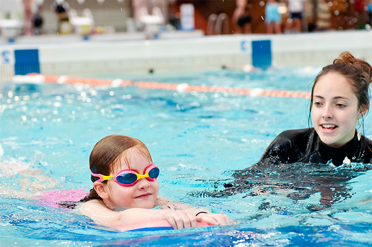 тренер учит ребёнка плавать в бассейне