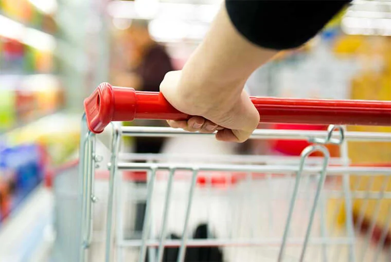 женщина катит продуктовую тележку в супермаркете